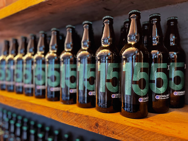 Row of XT Brewing Co XT 15 beer bottles on a wooden shelf in the taproom at XT Brewing Co in Long Crendon
